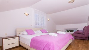 A bedroom with a bed, a nightstand, a chair, a TV, and a window with curtains. - Apartment Cypress (Okrug Gornji)