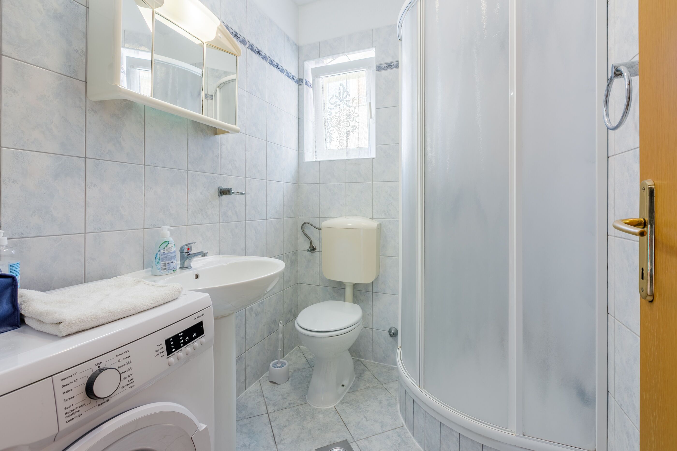 Ein Badezimmer mit einem weißen Waschbecken, einer Toilette und einer Duschkabine.