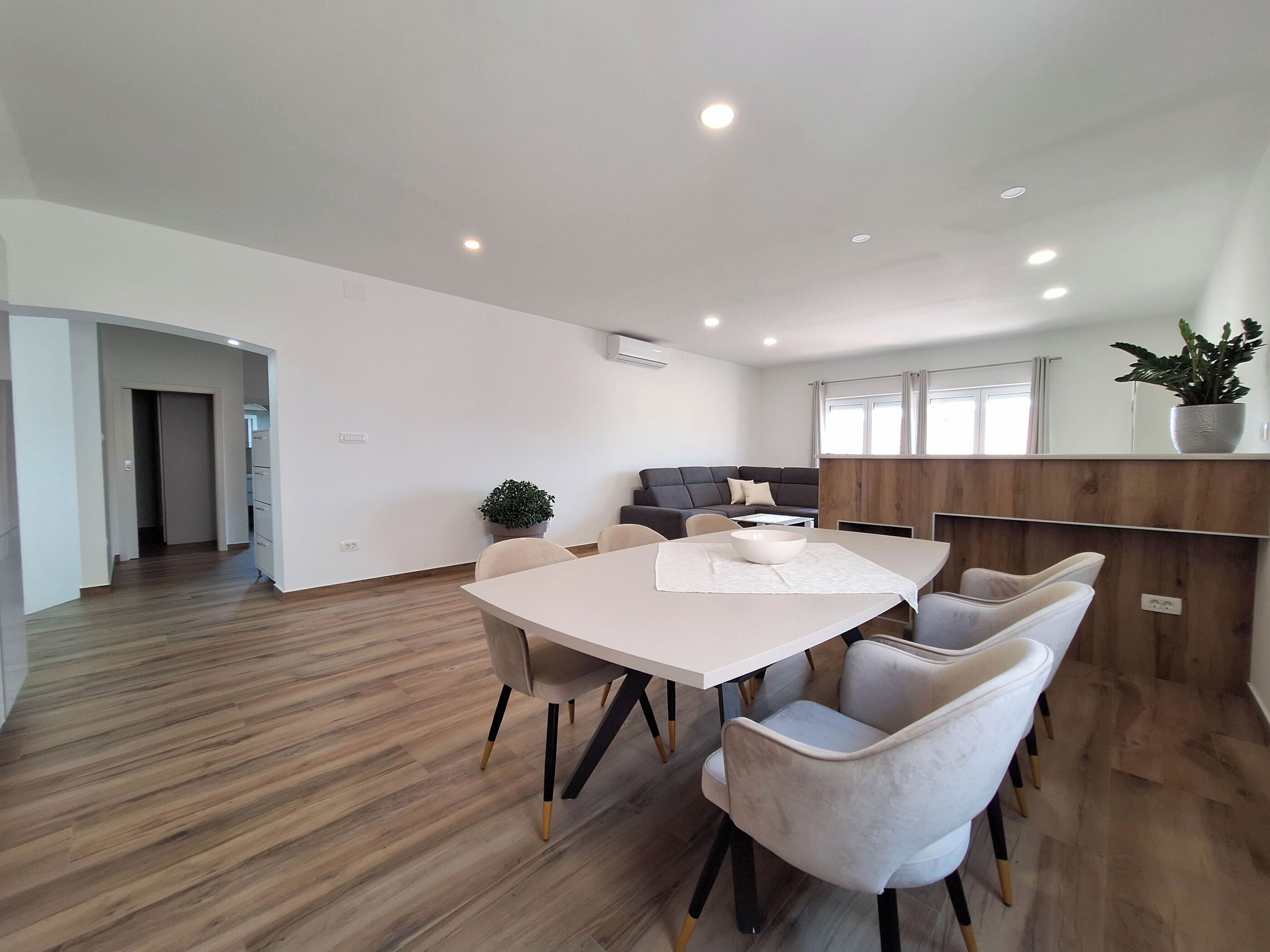 A modern living room with a dining area, a sofa, and a wooden accent wall.