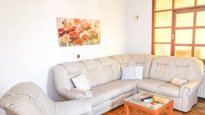 A living room with a beige sectional sofa, a glass coffee table, and a wooden parquet floor. - Apartment Donna (Biograd)