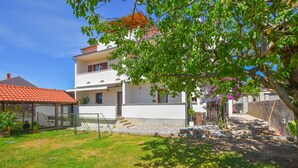 A two-story house with a red-tiled roof, a covered patio, and a well-maintained garden. - Apartment Donna (Biograd)