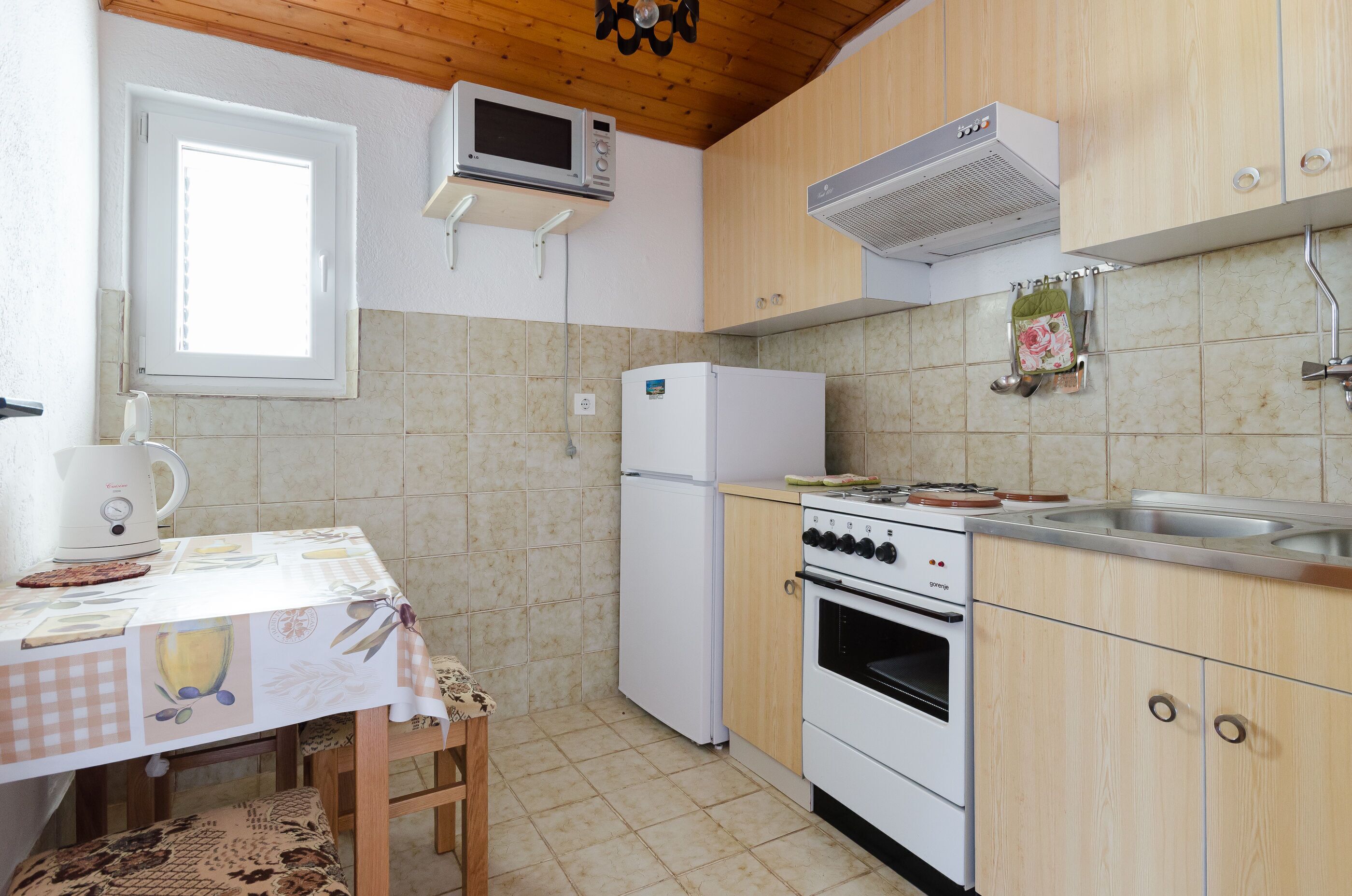 Una cocina compacta equipada con microondas, refrigerador, estufa y lavadero.