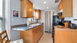 A compact kitchen with wooden cabinets, a countertop, a sink, and a stove.