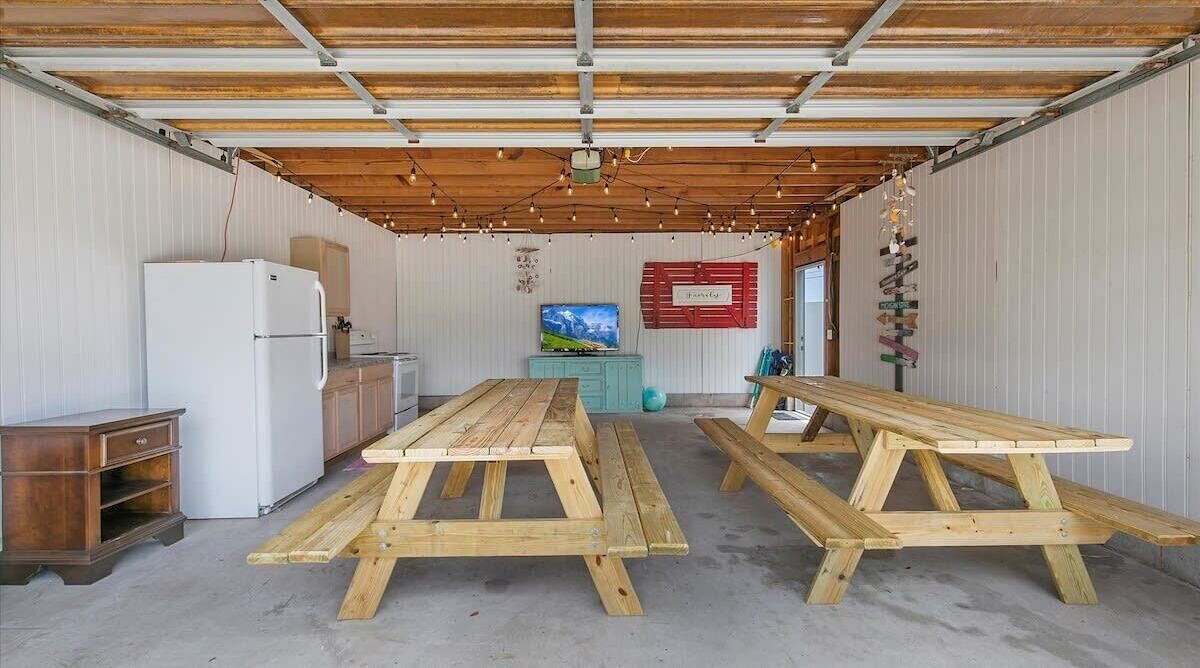 Una cocina rústica con mesas de madera, un refrigerador y un televisor.