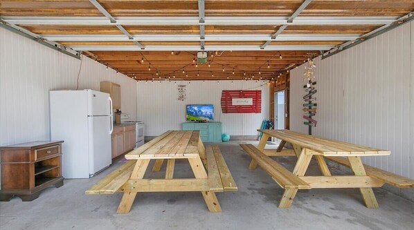 A rustic kitchen with wooden tables, a refrigerator, and a television.