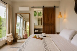 A bedroom with a bed, a wardrobe, a mirror, and a view of the outdoors.
