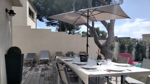 An outdoor patio with a long dining table, chairs, and an umbrella. - ⛰️☀️Villa Le Saint Clair - Entre Pins, Colline & Méditerranée in Sète 🌊🌲 (Sète)