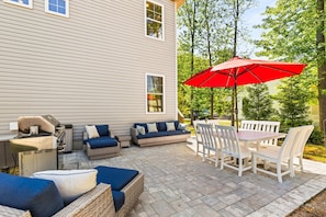 A patio with outdoor furniture, a grill, and a red umbrella.