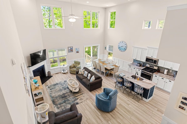 A spacious living area with a fireplace, seating, a dining area, and a kitchen with modern appliances.