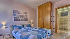 Ein Schlafzimmer mit Bett, Holzschrank, Nachttisch, Wandlampe und einem Gemälde.