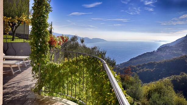 Eine Terrasse mit Blick auf eine Berglandschaft und ein Gewässer.