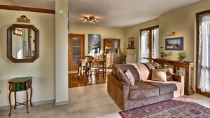 Ein geräumiges Wohnzimmer mit einer großen Couch, einem Essbereich mit Holztisch und -stühlen und einer Küche im Hintergrund.