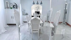 A dining area with a white table and chairs, a chandelier, and decorative items on the wall.