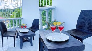 A balcony with wicker furniture and a table with two red drinks.