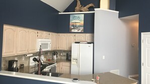 A kitchen with white cabinets, a microwave, a refrigerator, and a small island with a sink. - Waterfront home;heated pool & spa: walk to public beach; food, bars, live music! (Port Clinton)