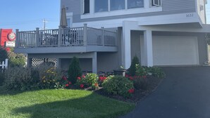 A two-story house with a balcony, a garage, and a well-maintained lawn with flowers. - Waterfront home;heated pool & spa: walk to public beach; food, bars, live music! (Port Clinton)