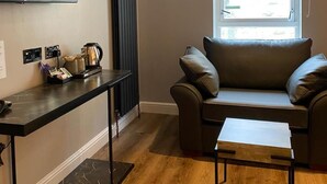 Un salón moderno con televisor de pantalla plana, un radiador negro, una ventana con persianas, un sofá de cuero y una mesa de centro de madera.