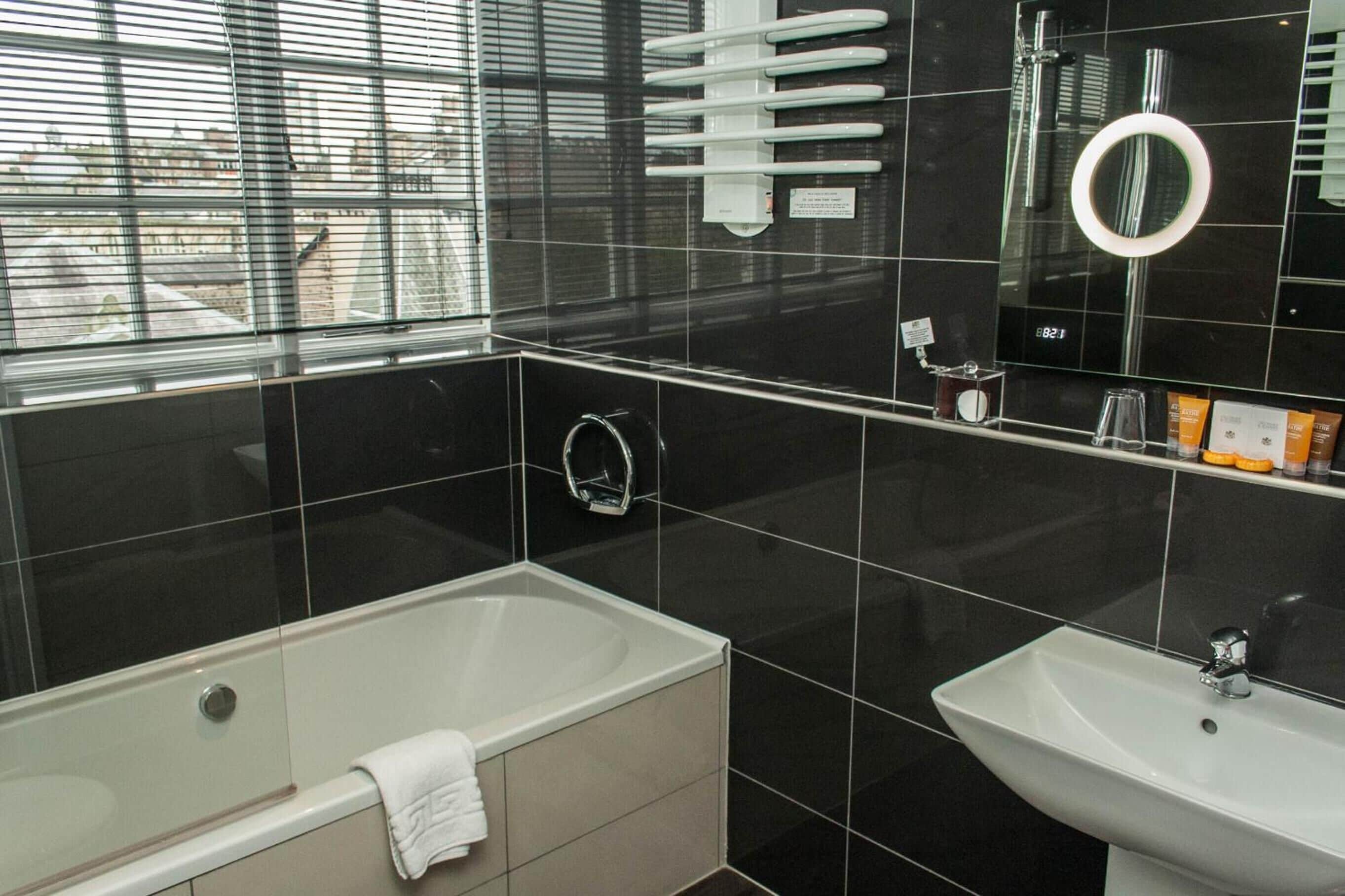 Een moderne badkamer met een bad, een wastafel en een grote spiegel.