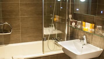 A modern bathroom with a glass-enclosed shower, a white sink, and a mirror with a circular light.