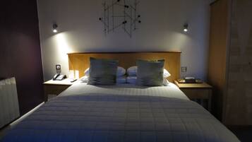 Habitación de hotel con una cama grande, dos mesitas de noche, cabecera de madera y una obra de arte abstracta colgada en la pared.