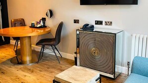 Una sala de estar moderna con una mesa de comedor redonda de madera, un sofá azul, un televisor de pantalla plana montado en la pared y un aparador decorativo.