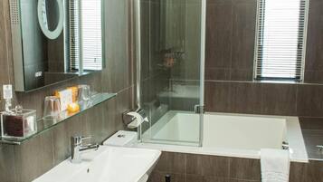 A modern bathroom with a glass-enclosed shower, a white bathtub, a toilet, and a sink.