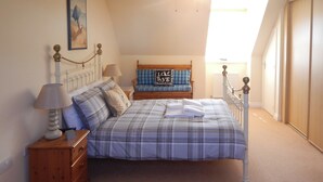 A bedroom with a bed, nightstands, a dresser, a lamp, and a painting on the wall. - 4 bedroom accommodation in Sidmouth (Sidmouth)