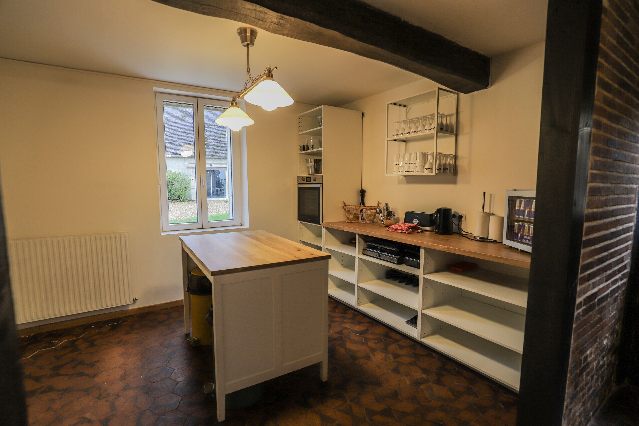A compact kitchen with a window, a radiator, and a wooden counter.
