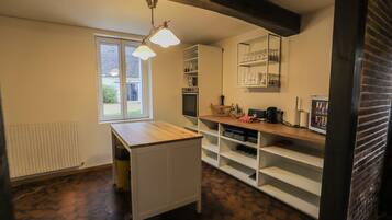 A compact kitchen with a window, a radiator, and a wooden counter.