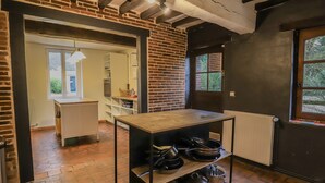 Una cocina con paredes de ladrillo visto, una mesa de madera con ollas y vistas al exterior a través de una ventana.