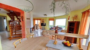 Un'ampia zona giorno con tavolo da pranzo, sedie, divano e televisione.