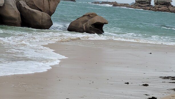 Une plage avec de gros rochers et des vagues.