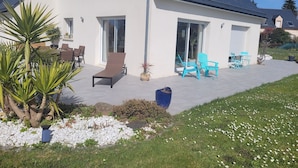 Une maison moderne dotée d’un patio, de mobilier d’extérieur et d’un jardin.