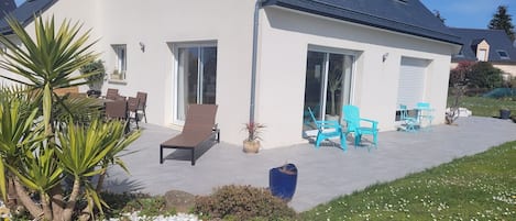 A modern house with a patio, outdoor furniture, and a garden area.