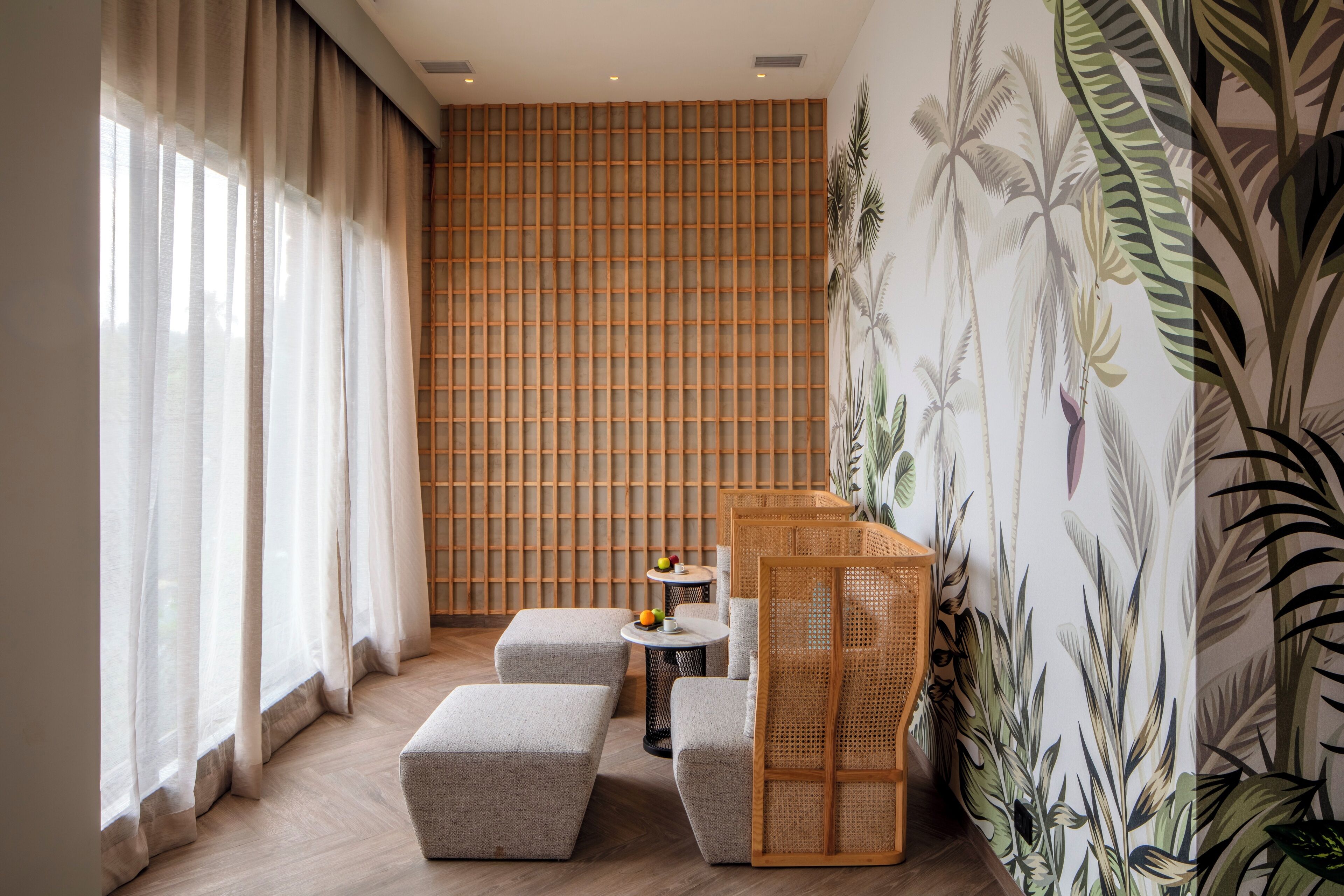 Une pièce moderne avec un plancher en bois, un canapé, une petite table ronde sur laquelle sont disposés des fruits, et un mur orné d’un motif en réseau.