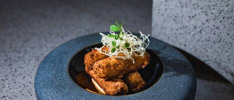 A round, dark blue ceramic plate with a food item and garnish, placed on a speckled surface.