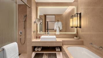 A modern bathroom with a large mirror, a white sink, a bathtub, and a shower.