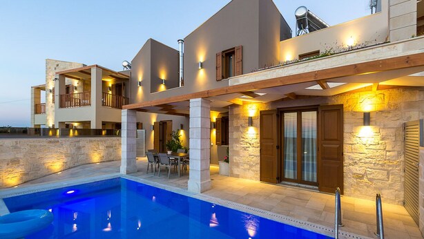 Ein modernes Haus mit Pool, Steinmauern und Holzbalkonen.