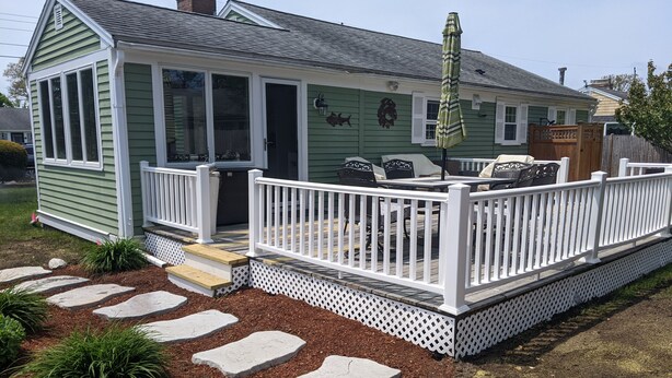 A green house with a white porch, stone steps, and outdoor furniture. - Walk to the beach- Completely renovated 3 bedrooms house, central A/C (Dennis)