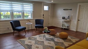 A living room with two blue armchairs, a yellow sofa, a coffee table, and a patterned rug. - Walk to the beach- Completely renovated 3 bedrooms house, central A/C (Dennis)