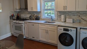 A modern kitchen with white cabinets, a built-in stove, a sink, and a dishwasher. - Walk to the beach- Completely renovated 3 bedrooms house, central A/C (Dennis)