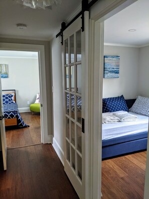 A bedroom with a bed, a window, and a door leading to another room.