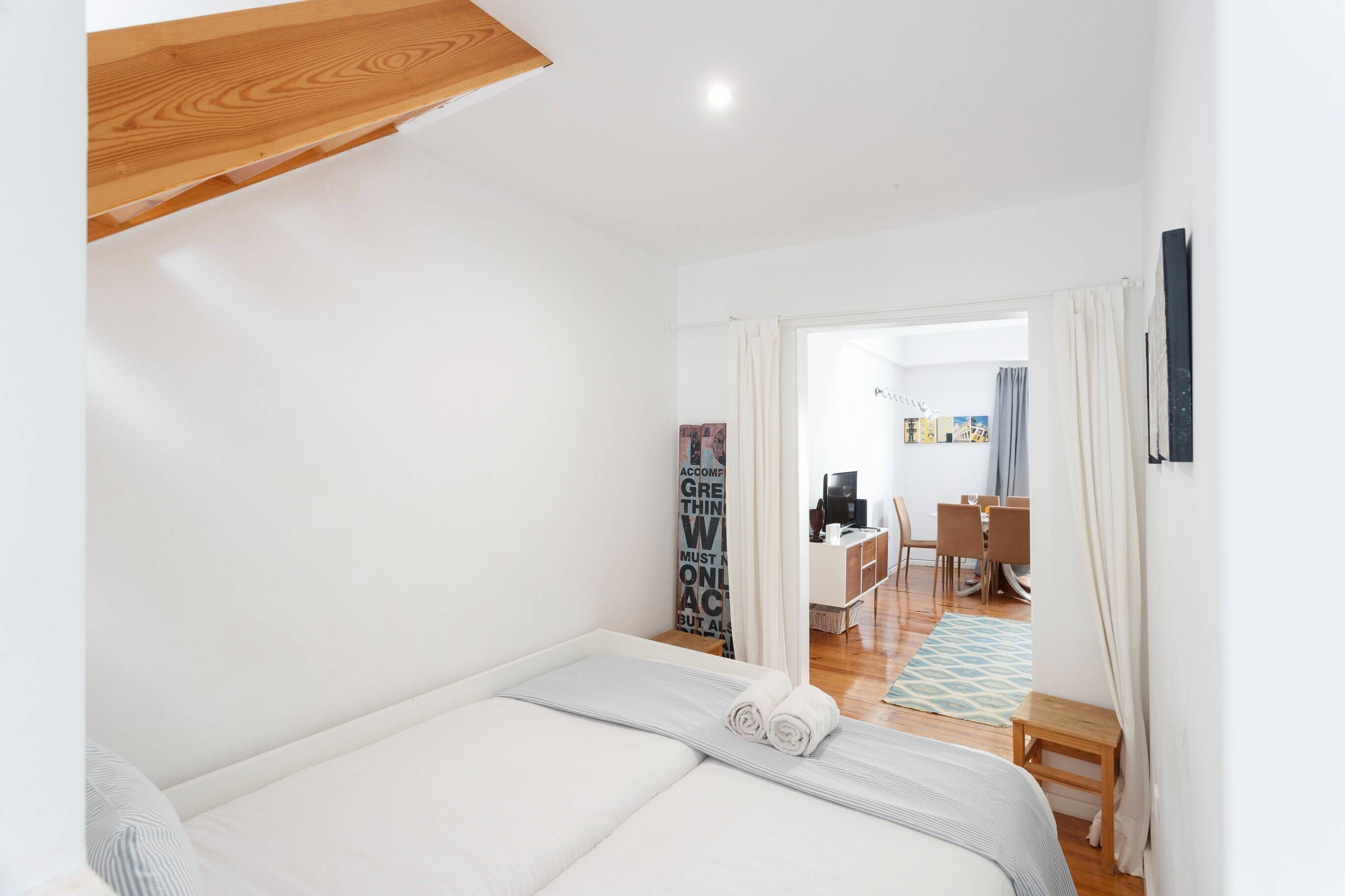 Une chambre à coucher avec un lit, un plafond en bois, un bureau et une chaise au fond.