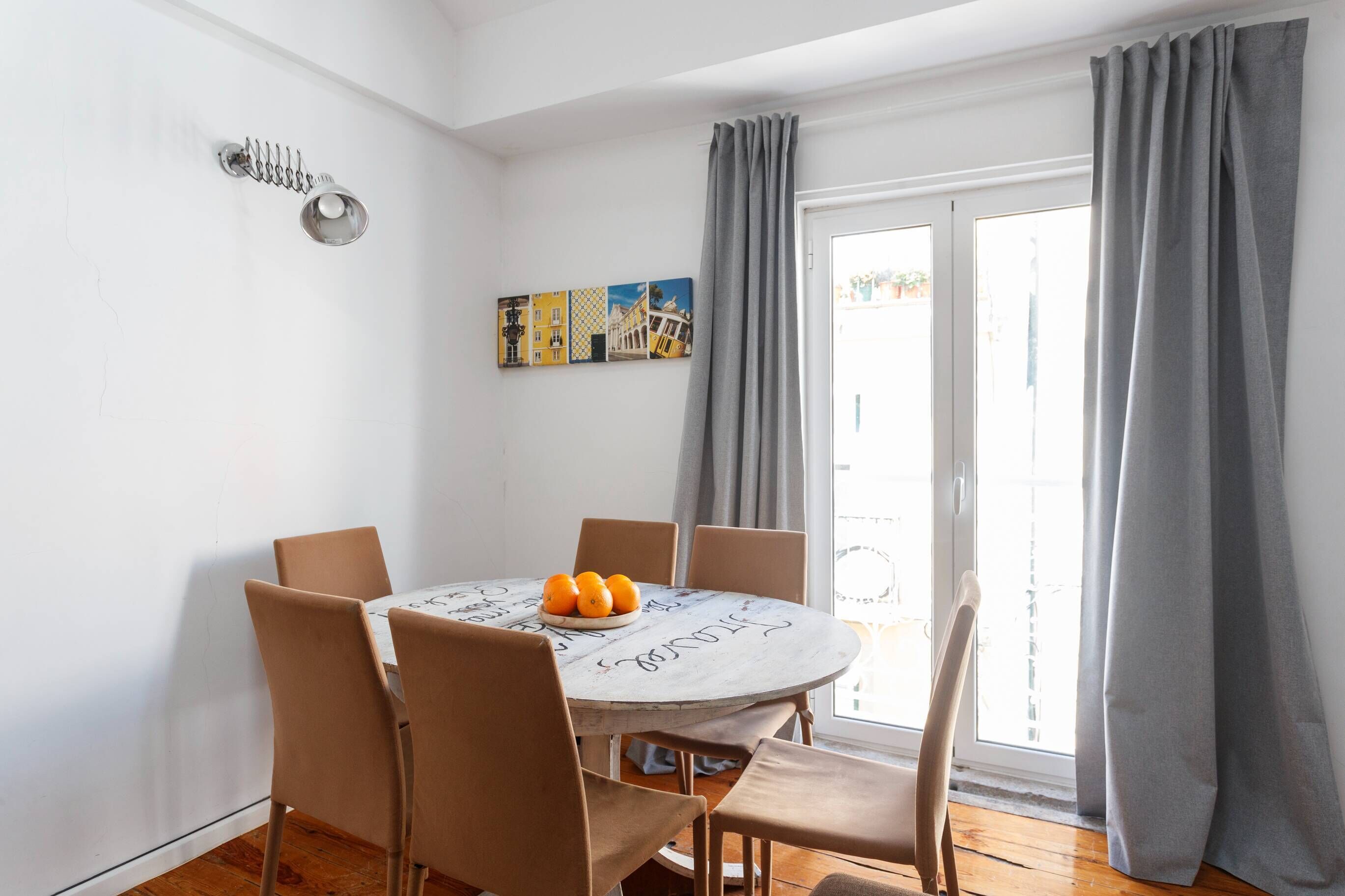 A dining area with a round table, six chairs, and a plate of oranges.