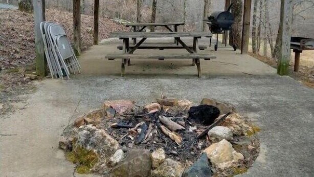 Ein hölzernes Pavillon mit Picknicktischen und einem Feuerkorb.
