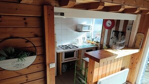 Et kompakt køkken med gasblus, mikroovn og en lille ovn.
