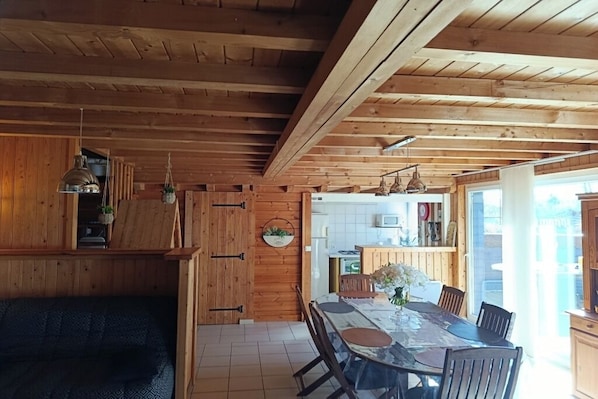 Un interior de madera con una mesa de comedor, sillas, un sofá y una zona de cocina.