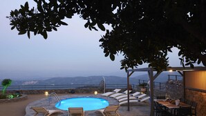An outdoor pool area with lounge chairs, a dining table, and a view of the mountains. - Irma Villa, a Secluded Sanctuary (Krousonas)