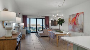 Un vaste espace de vie avec balcon, une table à manger avec des chaises et un grand tableau abstrait accroché au mur.