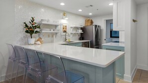 Une cuisine moderne dotĂ©e dâun Ăźlot central, de meubles blancs et dâappareils Ă©lectromĂ©nagers en acier inoxydable.